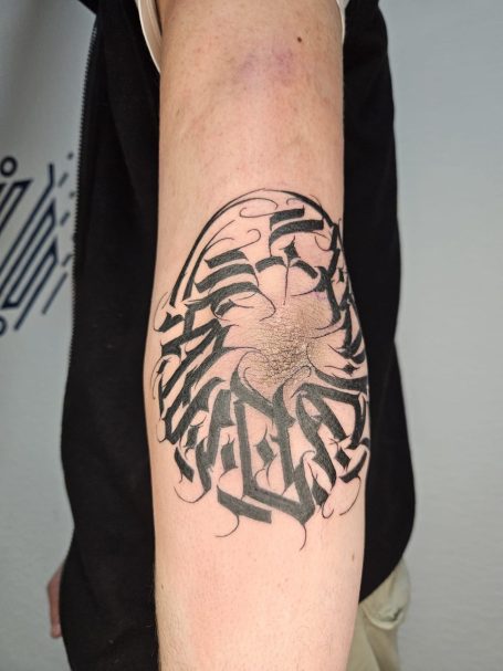 Schwarz-weißer Tätowierung auf einem Unterarm, abstraktes design mit geschwungenen Linien.