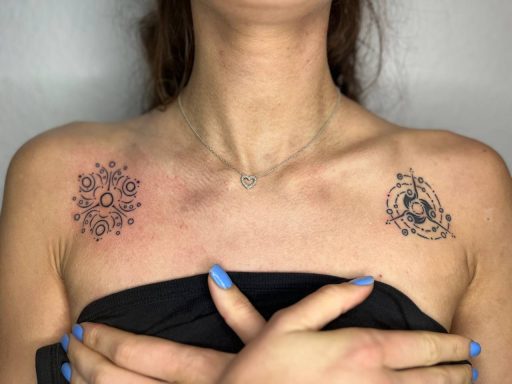 Zwei schwarze Tattoos auf den Schultern, eines mit mandalaähnlichem Muster.