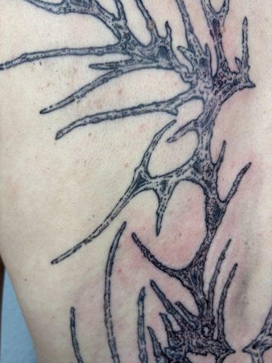 Tattoo eines abstrakten, baumartigen Musters auf der Haut.