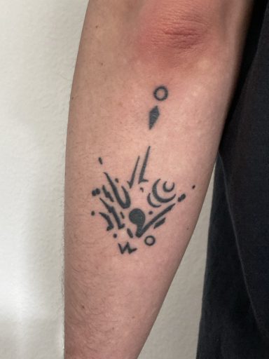 Schwarzes Tattoo auf dem Unterarm mit abstrakten Linien und Formen.