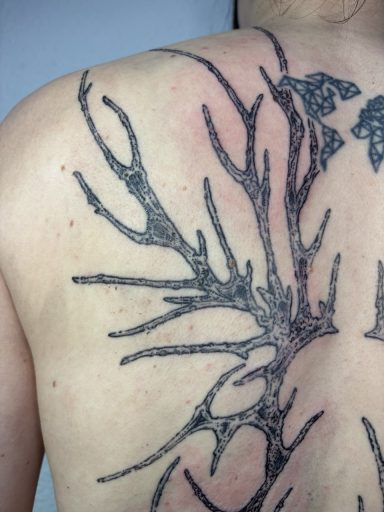 Tattoo eines verzweigten Baumdesigns auf dem Rücken.
