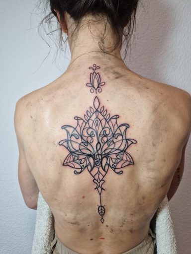 Tattoo eines detaillierten Mandala-Designs auf dem Rücken einer Person.