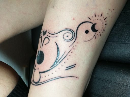 Tattoo auf dem Arm mit abstrakten Formen, einem Mond und einem Sonnensymbol.