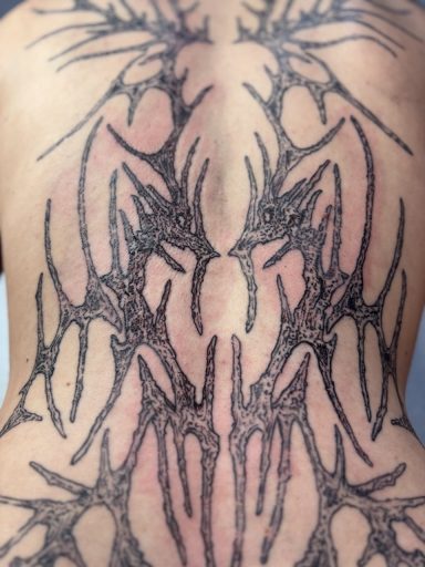 Schwarzer, kunstvoller Rücken-Tattoo mit symmetrischen, spitzen Mustern.