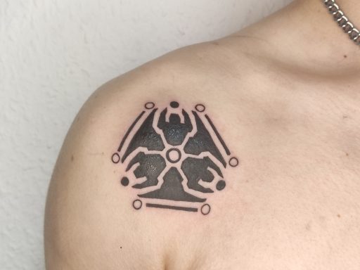Tätowierung auf dem Oberarm mit geometrischem Design und symbolischen Elementen.