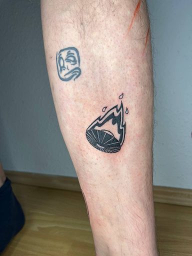 Tattoo auf dem Bein mit einem Wassermelonen-Motiv und einer Flamme darüber.