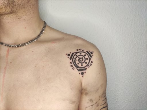 Schwarzes Tattoo in geometrischem Design auf der Schulter eines Mannes.